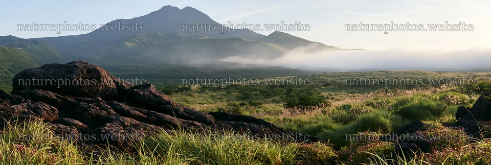 Kumamoto volcanic meadow dark rock foreground under morning light – nature photos 13690x4602